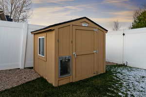 Outdoor structure at dusk with a fenced backyard and a storage shed