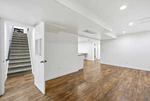 Finished below grade area featuring recessed lighting, stairs, and dark wood-type flooring