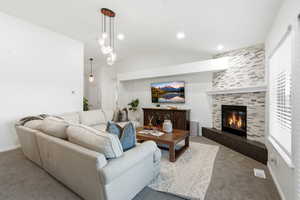 Carpeted living room featuring a fireplace and vaulted ceiling