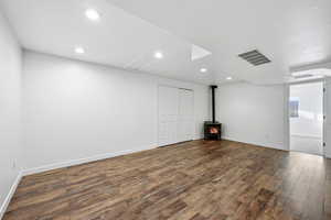 Spare room featuring a wood stove, dark wood-style flooring, and recessed lighting