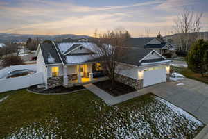 View of front facade with stone siding, stucco siding, driveway, and covered porch