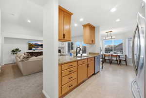 Kitchen featuring light stone counters, stainless steel appliances, recessed lighting, a fireplace, and open floor plan
