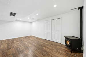 Basement featuring a wood stove, recessed lighting, and dark wood-type flooring