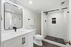 Bathroom with vanity, a marble finish shower, dark tile patterned floors, and recessed lighting
