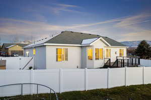 View of front of home featuring a shingled roof, a fenced backyard, and stucco siding