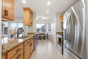Kitchen featuring stainless steel appliances, light stone counters, recessed lighting, hanging light fixtures, and light tile patterned floors