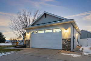 View of front of house with stone siding, stucco siding, a garage, and concrete driveway