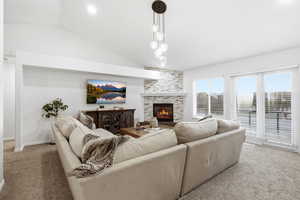 Carpeted living room with lofted ceiling and a fireplace