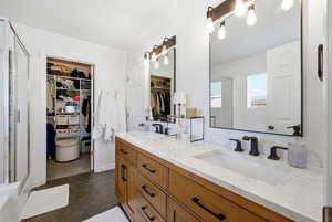 Bathroom with a spacious closet, a stall shower, and double vanity