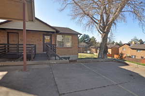 View of front facade featuring brick siding, uncovered parking, and a residential view