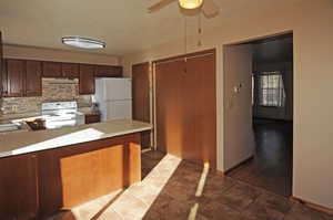 Kitchen with white appliances, light countertops, a textured ceiling, a peninsula, and under cabinet range hood