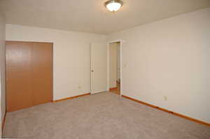 Unfurnished bedroom with a closet, a textured ceiling, and carpet floors