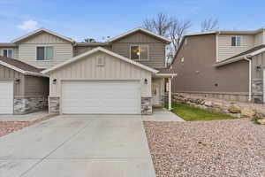 View of front of house featuring board and batten siding, stone siding, and concrete driveway