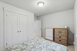 Bedroom featuring a closet, light colored carpet, and a textured ceiling