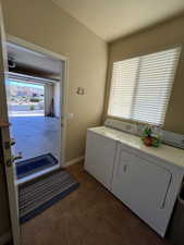 Laundry area featuring independent washer and dryer and dark tile patterned floors