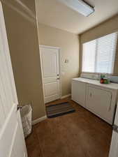 Washroom featuring separate washer and dryer and dark tile patterned flooring