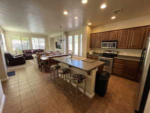 Kitchen with a textured ceiling, dark countertops, stainless steel appliances, open floor plan, and a chandelier