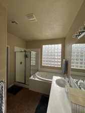 Full bathroom featuring vanity, a whirlpool tub, a stall shower, a textured ceiling, and dark tile patterned flooring