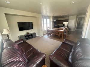 Carpeted living area featuring a chandelier, tile patterned floors, recessed lighting, and a textured ceiling