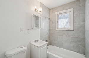 Bathroom with vanity, shower / bath combination, and a textured wall