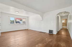 Spare room with plenty of natural light, arched walkways, and hardwood / wood-style floors