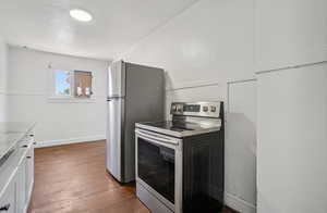 Kitchen featuring appliances with stainless steel finishes, dark wood-style floors, white cabinets, and light countertops