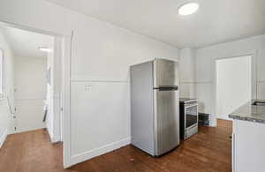 Kitchen with stainless steel appliances, dark wood finished floors, white cabinets, and light stone countertops