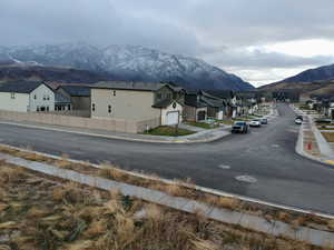 View of asphalt street with sidewalks, a mountain view, a residential view, and curbs
