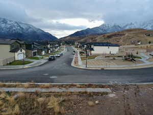 View of asphalt street with curbs, a mountain view, sidewalks, and a residential view