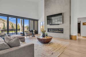 Living room with a high ceiling, a fireplace, light wood-style floors, and healthy amount of natural light