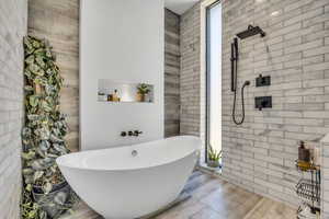 Full bath with a freestanding tub, brick wall, tile walls, and a tile shower