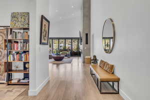 Hallway featuring light wood finished floors, a high ceiling, and recessed lighting