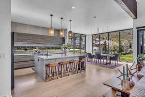 Kitchen featuring modern cabinets, light stone counters, pendant lighting, a kitchen breakfast bar, and floor to ceiling windows