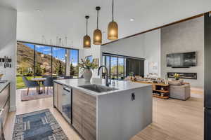Kitchen featuring modern cabinets, hanging light fixtures, light wood-style flooring, open floor plan, and an island with sink