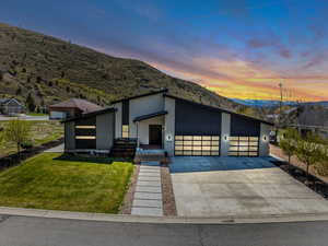 Contemporary home featuring a yard, stucco siding, driveway, a mountain view, and a porch