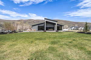 Rear view of house with a mountain view, a yard, and a patio