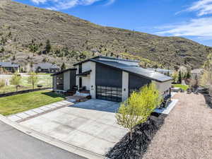 View of front of property featuring driveway, an attached garage, a front lawn, stucco siding, and a mountain view