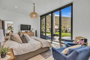 Bedroom with a wall of windows, access to exterior, wood finished floors, and recessed lighting