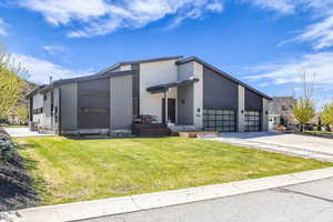 Contemporary house with a front lawn, driveway, a garage, and stucco siding