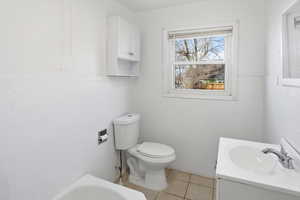Bathroom featuring tile walls, vanity, a tub to relax in, light tile patterned floors, and wainscoting