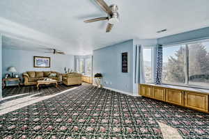 Living area featuring ceiling fan and a textured ceiling