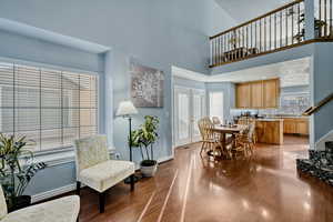 Dining space with light wood-style flooring, french doors, a towering ceiling, and stairway