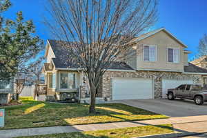 View of front of home featuring a front yard, stucco siding, concrete driveway, brick siding, and a shingled roof