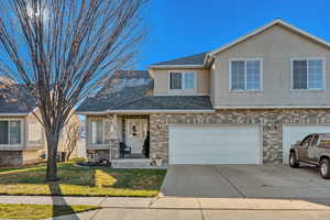 View of front of property with brick siding, concrete driveway, stucco siding, roof with shingles, and a front lawn