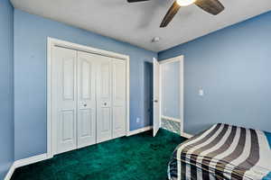 Carpeted bedroom with a ceiling fan and a closet