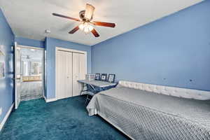 Bedroom featuring dark colored carpet, a closet, and a ceiling fan