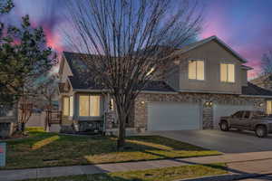 Traditional-style house featuring a yard, brick siding, concrete driveway, stucco siding, and an attached garage