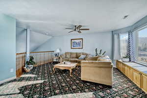 Living room featuring a ceiling fan, a textured ceiling, and dark carpet