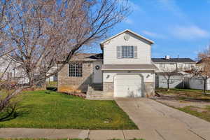 Tri-level home featuring brick siding, a garage, and driveway
