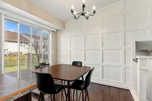 Dining room featuring a decorative wall, a chandelier, and dark wood-type flooring
